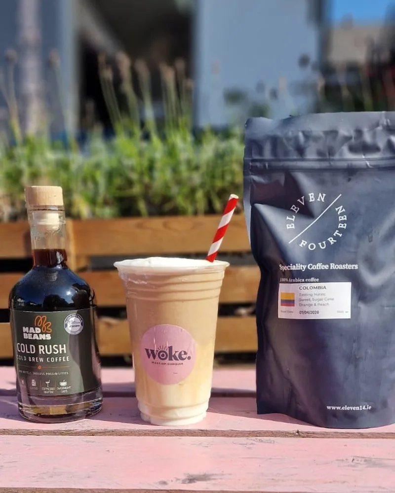 Cold brew, a Woke iced coffee and a bag of Eleven Fourteen beans on the pink bench