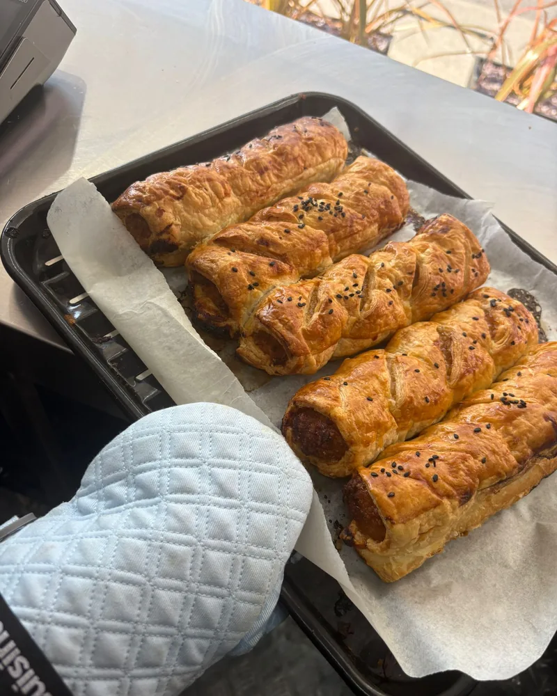 A tray of sausage rolls fresh from the oven, topped with black sesame